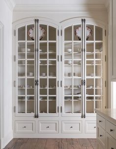 a white china cabinet with glass doors and drawers in a room that has wood floors