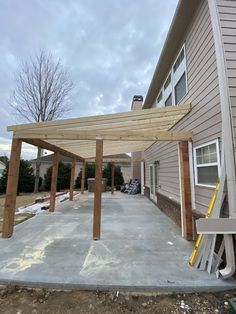 an outdoor covered patio in the process of being built with wood posts and sidings