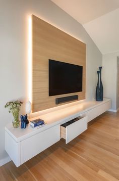 a flat screen tv sitting on top of a white entertainment center next to a wooden floor