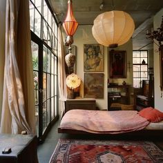 a bed sitting in a bedroom next to a window with lots of light hanging from it