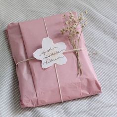 a pink gift wrapped in paper and tied with twine on top of a bed