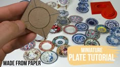 a hand holding a piece of paper with miniature plates on it next to other items