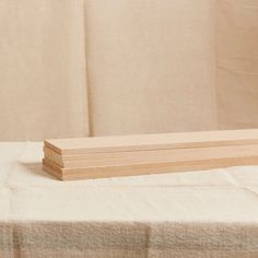 a stack of wooden boards sitting on top of a white table cloth covered tablecloth