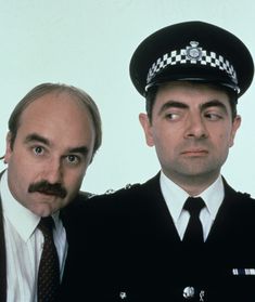 two men dressed in police uniforms posing for the camera with mustaches on their heads