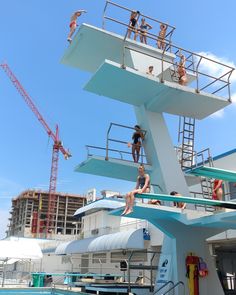 some people are hanging out on the top of a building while others swim in the pool