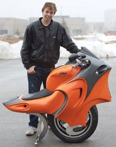 a man standing next to an orange motorcycle