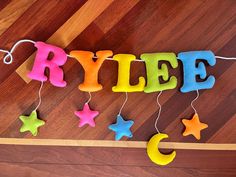 the word rice spelled out with felt stars and moon on a wooden floor next to string lights