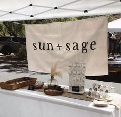 a table with a sign that says sun + sage on it and other items for sale