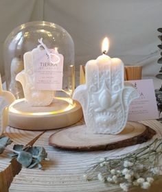 three candles sitting on top of a wooden table next to a glass dome filled with water