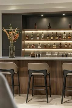 a bar with stools in front of it and bottles on the wall behind it