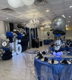 a room filled with balloons and tables covered in blue table cloths, black and white decor