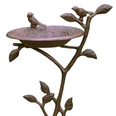 a bird sitting on top of a metal tray with leaves and flowers in it's center