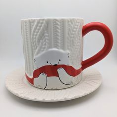 a red and white coffee cup with a polar bear on it sitting on a saucer