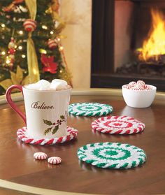 two mugs with hot chocolate and marshmallows are sitting on a table next to a christmas tree