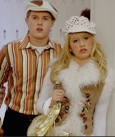 a man and woman dressed in costumes standing next to each other, one holding a purse