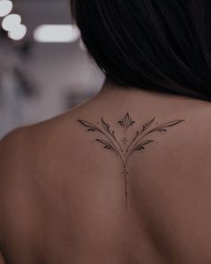 the back of a woman's neck with a flower tattoo on her left shoulder