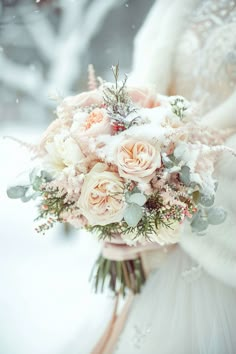 a bridal holding a bouquet of flowers in the snow