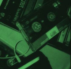 a pile of cassettes sitting next to each other on top of a table under a green light