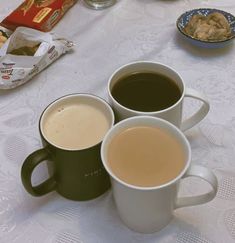 three cups of coffee sitting on top of a table next to cookies and crackers