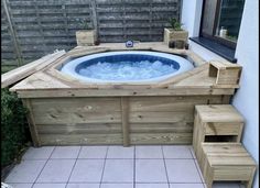 a hot tub sitting on top of a tiled floor next to a wooden bench and planter