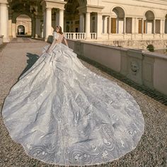 a woman in a wedding dress is standing on a stone walkway near an old building