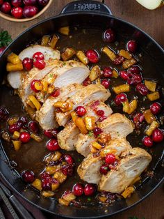 a pan filled with meat and cranberries on top of a table