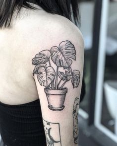 a black and white photo of a woman's arm with a potted plant on it