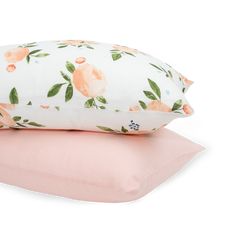 two pillows on top of each other, one pink and the other white with orange flowers