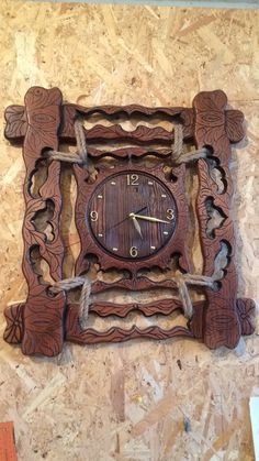 a wooden clock on the wall with chains around it's edges and an intricate design