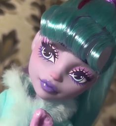 a close up of a doll with green hair and blue eyes, wearing pink eyeliners