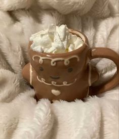 a mug filled with whipped cream sitting on top of a blanket