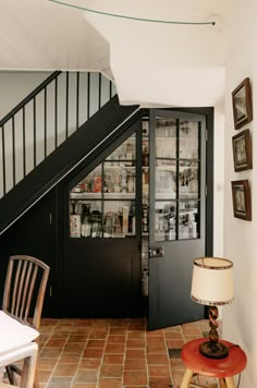 a room with a chair, table and bookshelf next to a stair case