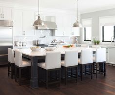 a large kitchen with white chairs and an island in front of the stove top oven