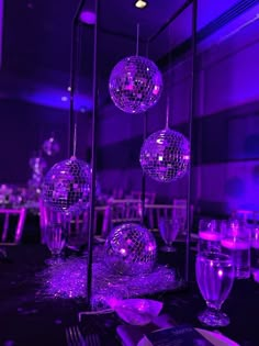 disco balls are hanging from the ceiling in front of tables and chairs at a party