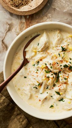 a white bowl filled with soup and garnished with herbs next to a wooden spoon