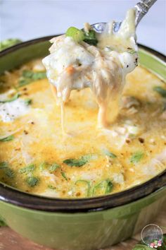 a spoonful of chicken and rice soup is being lifted from a green casserole dish