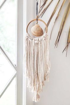 a white wall hanging next to a window filled with dried grass and palm leaves on it