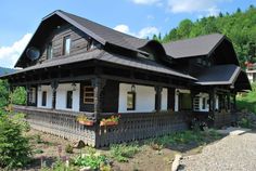 a large wooden house sitting on top of a lush green hillside next to a forest