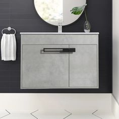 a white sink sitting under a round mirror next to a wall mounted faucet