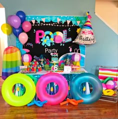 a birthday party with balloons, streamers, and decorations on the floor in front of a chalkboard