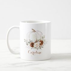 a white coffee mug with an autumn pumpkin and flowers on it