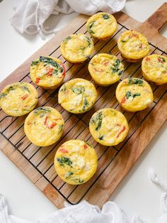 several muffins with spinach and red peppers on a cooling rack next to napkins