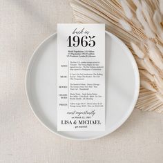 a white plate with a menu on it next to some pamylon stalks and a bottle of wine