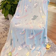 a blue blanket with cartoon characters on it sitting in front of a potted plant