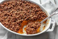 a casserole dish filled with meat and topped with orange sauce on a white cloth