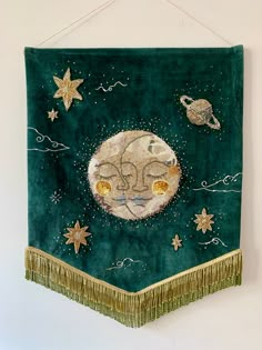 a green wall hanging with an image of the moon and stars on it's side