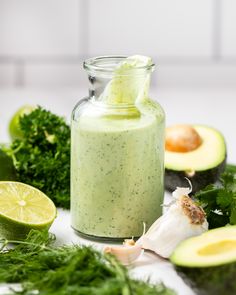 an avocado smoothie in a glass jar surrounded by fresh ingredients