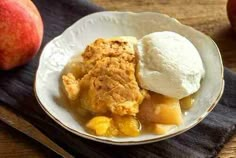 a bowl filled with fruit and ice cream on top of a wooden table next to an apple