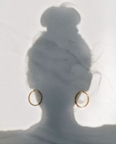 the shadow of a woman's head with large hoop earrings