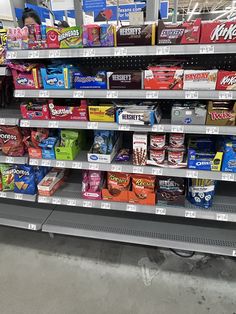 an empty grocery store shelf filled with snacks and other items, including candy bars or cereals